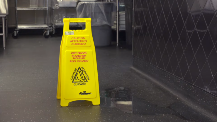 Yellow Wet Floor Sign Placed Near a Spill on A Kitchen Floor